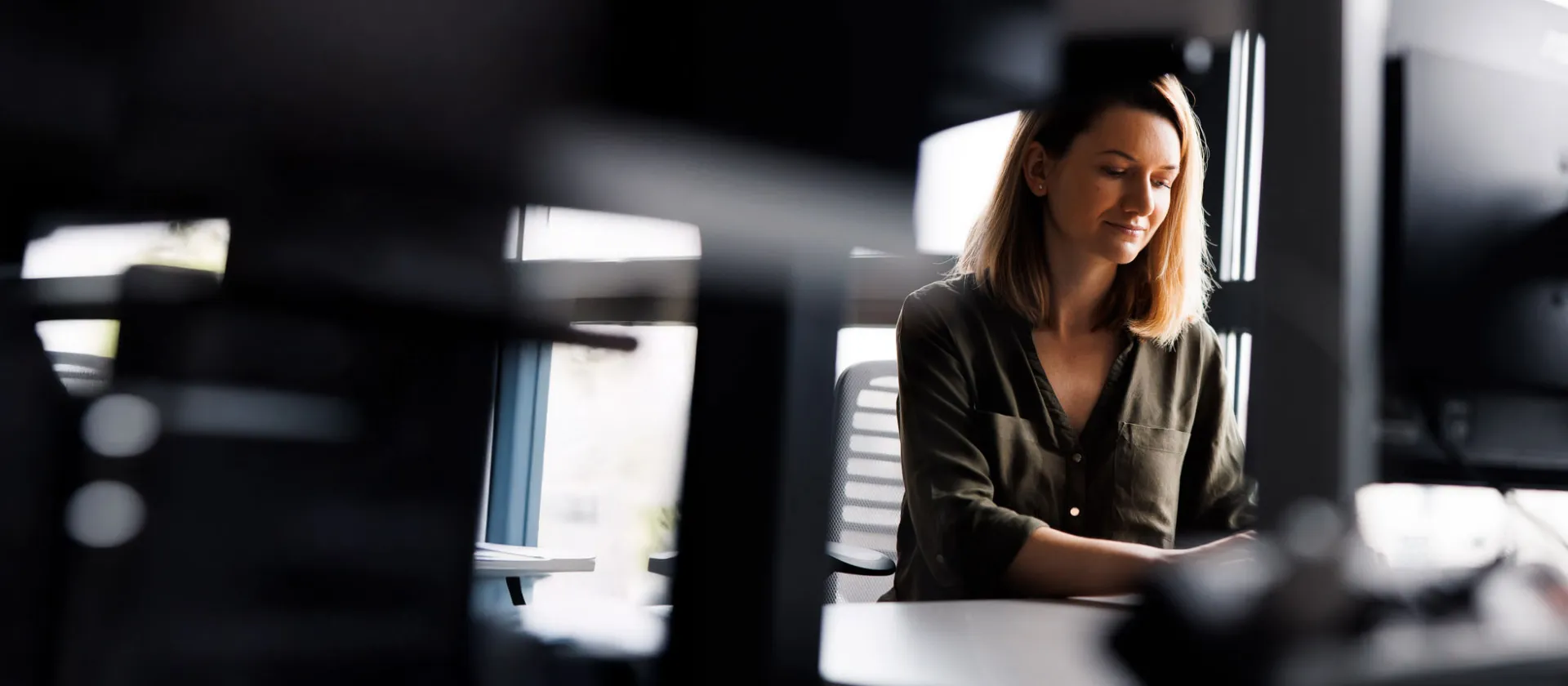Woman working at desk in modern office, focusing on a project in digital transformation and technology consulting.