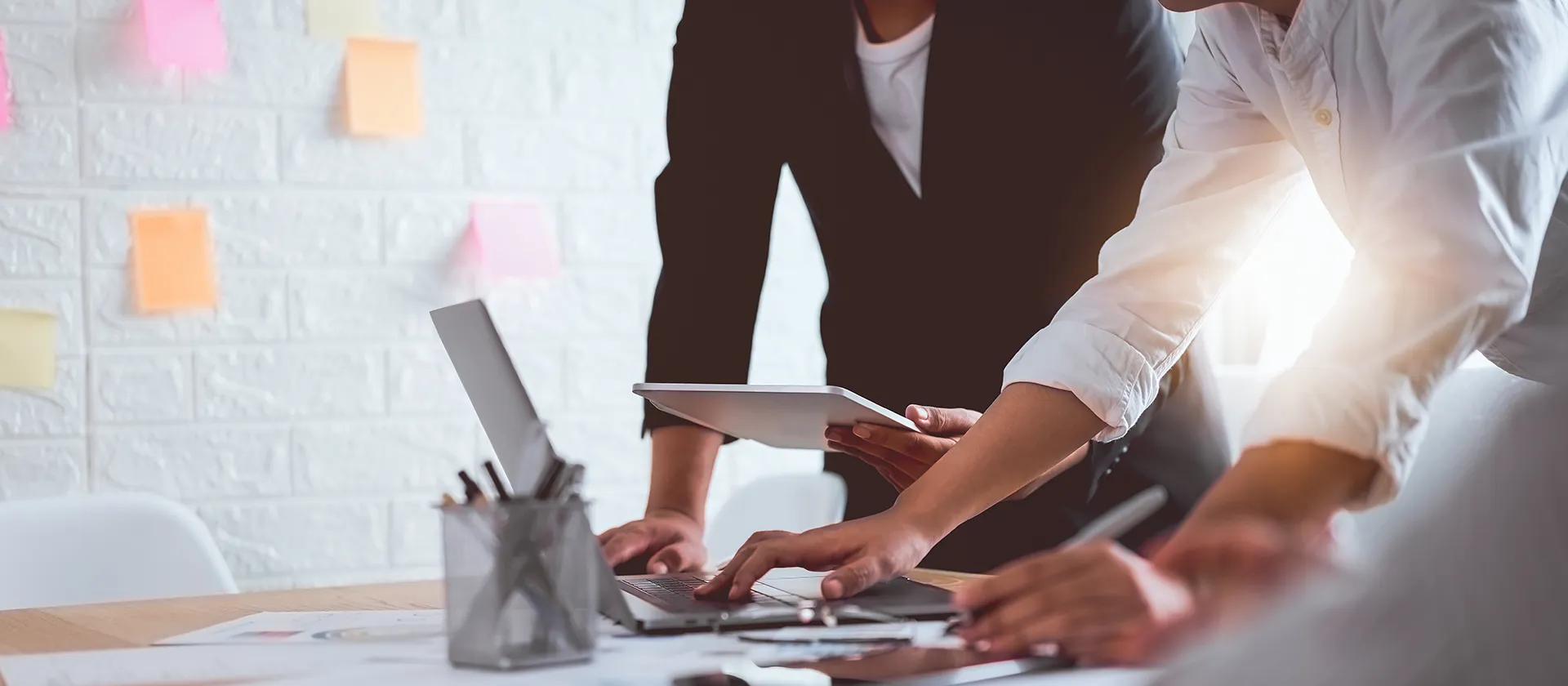 Business team collaborating on a digital project using laptops and tablets at a modern office workspace.