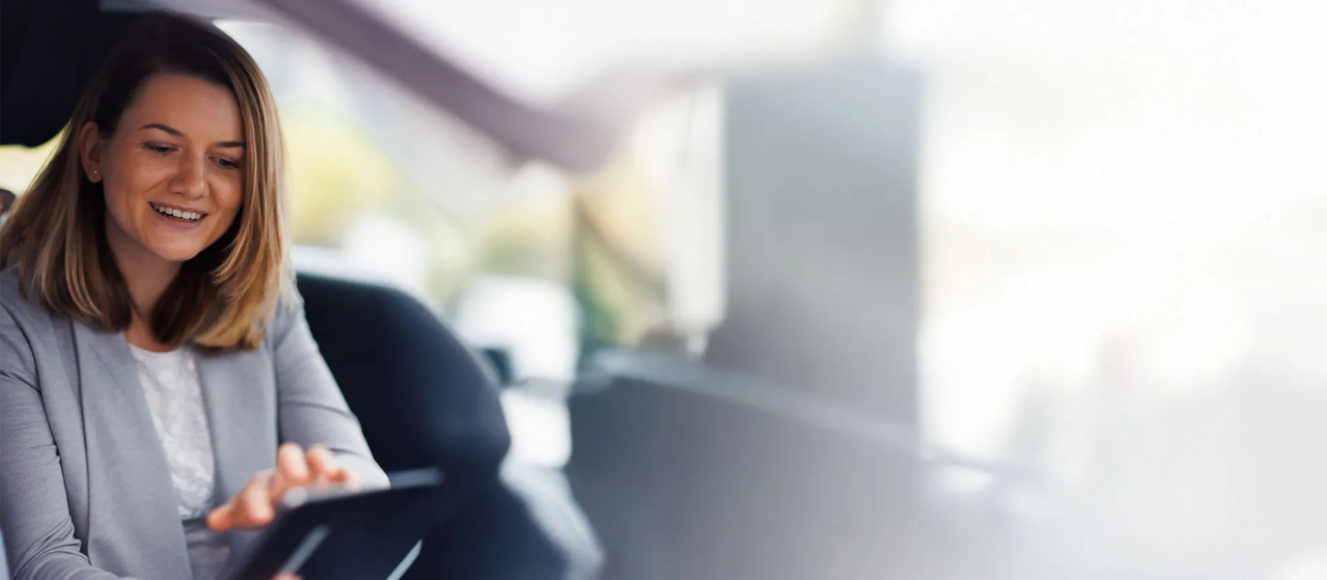 Smiling business consultant from msg Plaut demonstrating digital solutions on a tablet to a client in a bright, modern workspace.