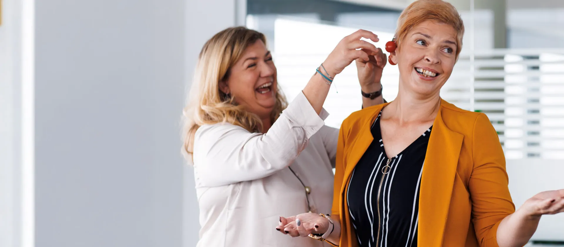 Two female colleagues at msg Plaut sharing a playful moment in the office, symbolizing a positive work culture and strong team spirit.