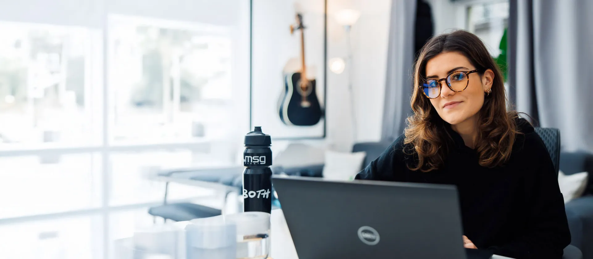 Woman working on a laptop in a bright, modern office, reflecting msg Plaut’s expertise in digital innovation and efficient workplace solutions.
