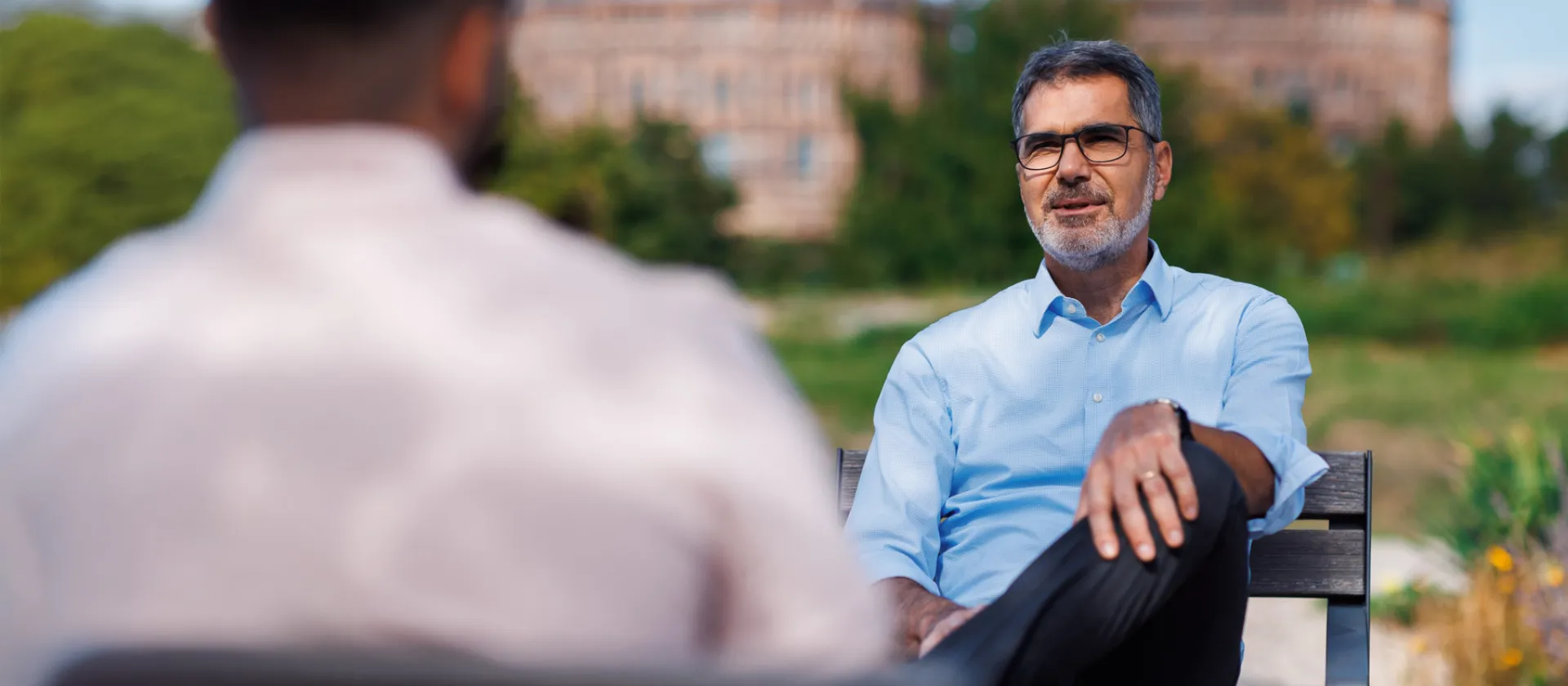 Senior executive discussing ESG strategies and corporate responsibility in an outdoor setting, with the historic Gasometer Vienna in the background.