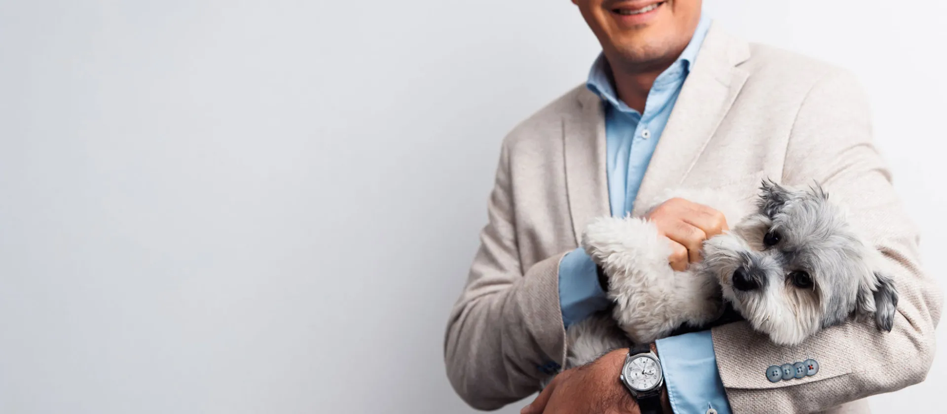 Business professional in a beige suit holding a small grey dog, reflecting msg plaut’s people-first culture and innovative approach to consulting and technology solutions.