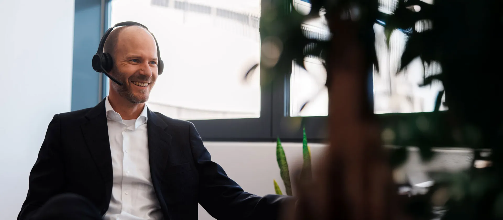 Smiling business professional in a video call wearing a headset in a bright modern office