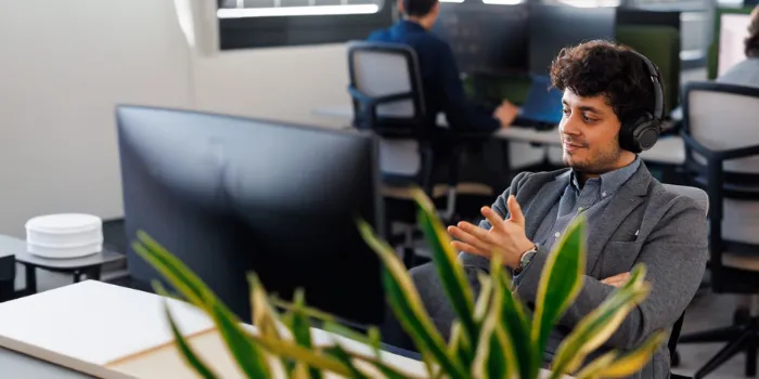 Man in modern office wearing headphones, engaged in a virtual meeting at msg Plaut, focusing on digital transformation and IT consulting.