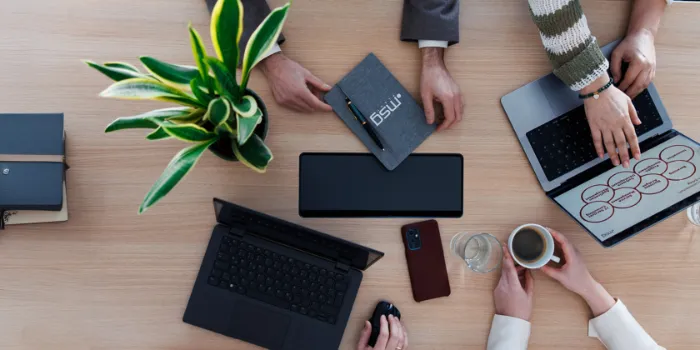 Top view of a collaborative business meeting with laptops, notebooks, coffee, and digital strategy tools, illustrating teamwork and planning in a consulting environment.
