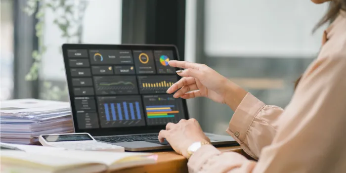 The female analyst utilizes a computer and a dashboard for business data analyze and a data management system with KPI. The concepts of technology, finance, operations, sales, and marketing. 
