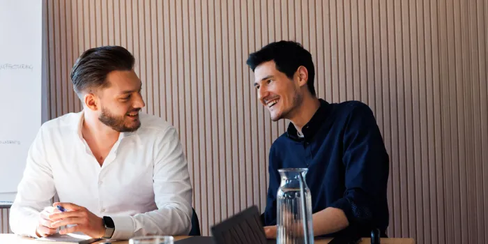 The picture shows two men sitting together, discussing a project.