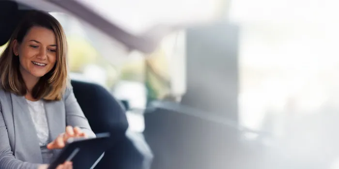 Smiling business consultant from msg Plaut demonstrating digital solutions on a tablet to a client in a bright, modern workspace.