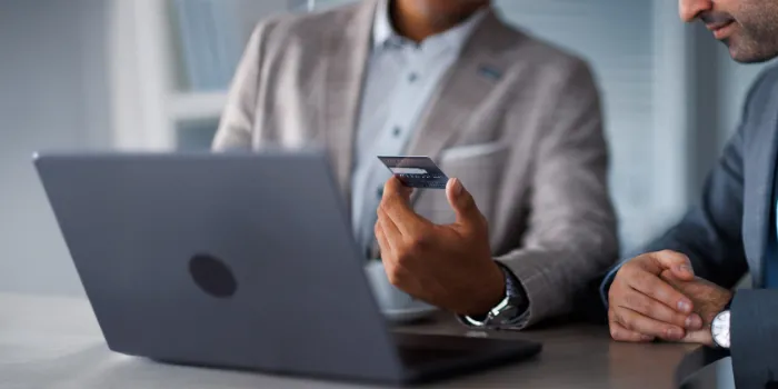 Close-up of two business professionals discussing digital payment and financial data using a laptop, symbolizing finance transformation and analytics in the SAP ecosystem.