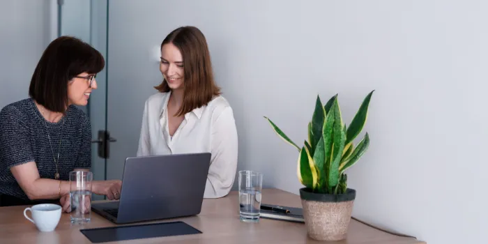 Two businesswomen collaborating on a laptop at the office, discussing digital transformation strategies at msg Plaut.