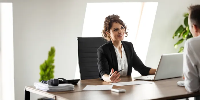 Smiling businesswoman in a modern office engaging in a professional conversation, symbolizing consulting, HR advisory, or a career interview setting.