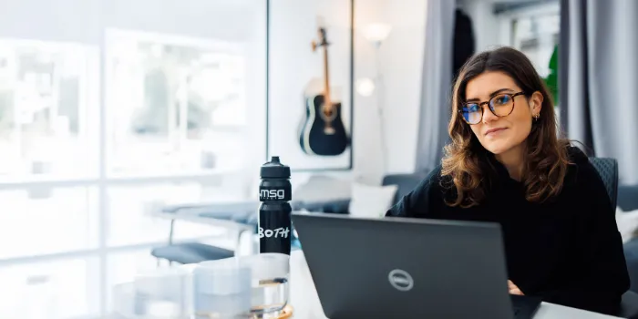 Woman working on a laptop in a bright, modern office, reflecting msg Plaut’s expertise in digital innovation and efficient workplace solutions.