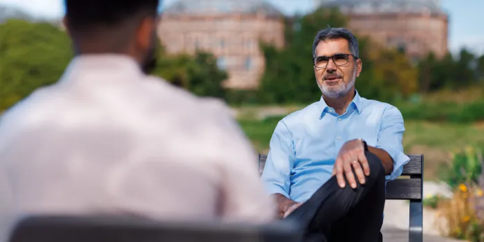 Senior executive discussing ESG strategies and corporate responsibility in an outdoor setting, with the historic Gasometer Vienna in the background.