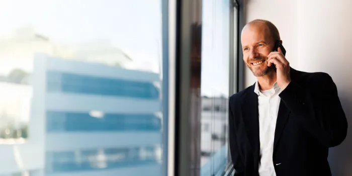 Business professional in a modern office, smiling while making a phone call, symbolizing confident communication and digital business consulting.