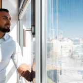 Confident business professional looking out of a modern office window with a cityscape view, symbolizing strategic thinking, leadership, and digital transformation.
