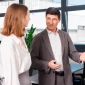 Businesswoman and businessman in a modern office space engaged in a professional conversation, symbolizing collaboration and consulting in a digital business environment.