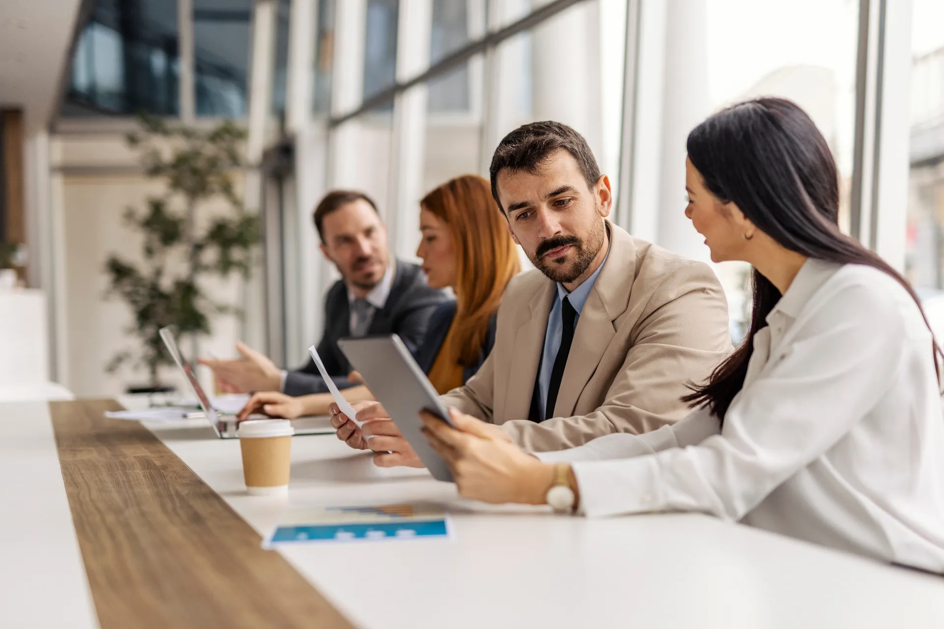 Two executives discussing data on tablet while sitting on a meeting at boardroom.