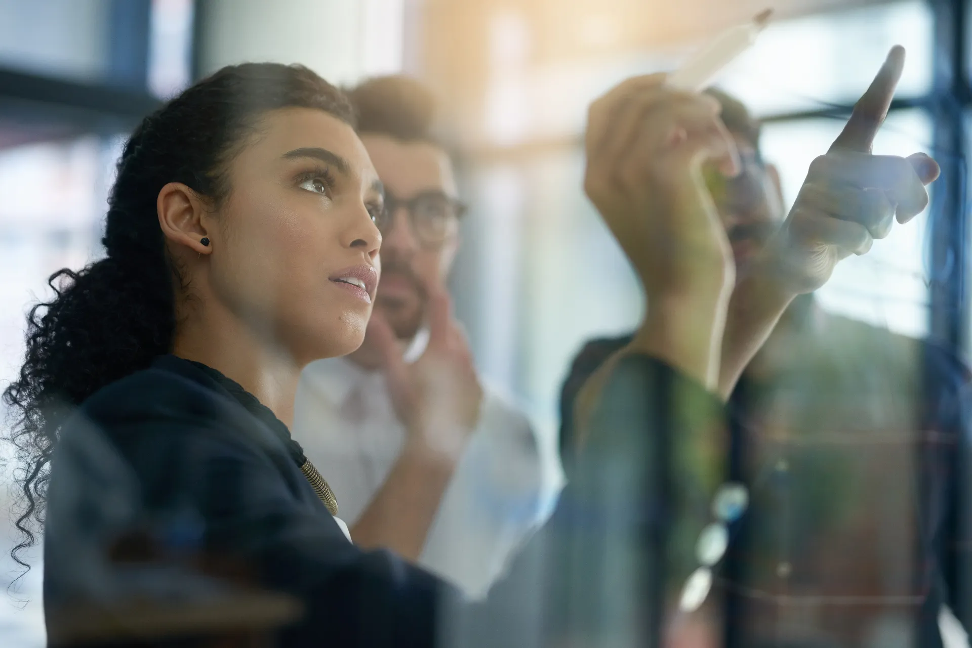 Shot of a group of colleagues brainstorming together on a glass wall in an office.