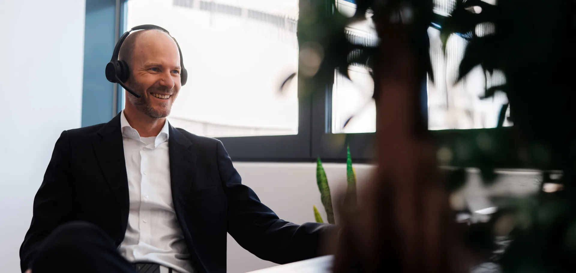 Smiling business professional in a video call wearing a headset in a bright modern office