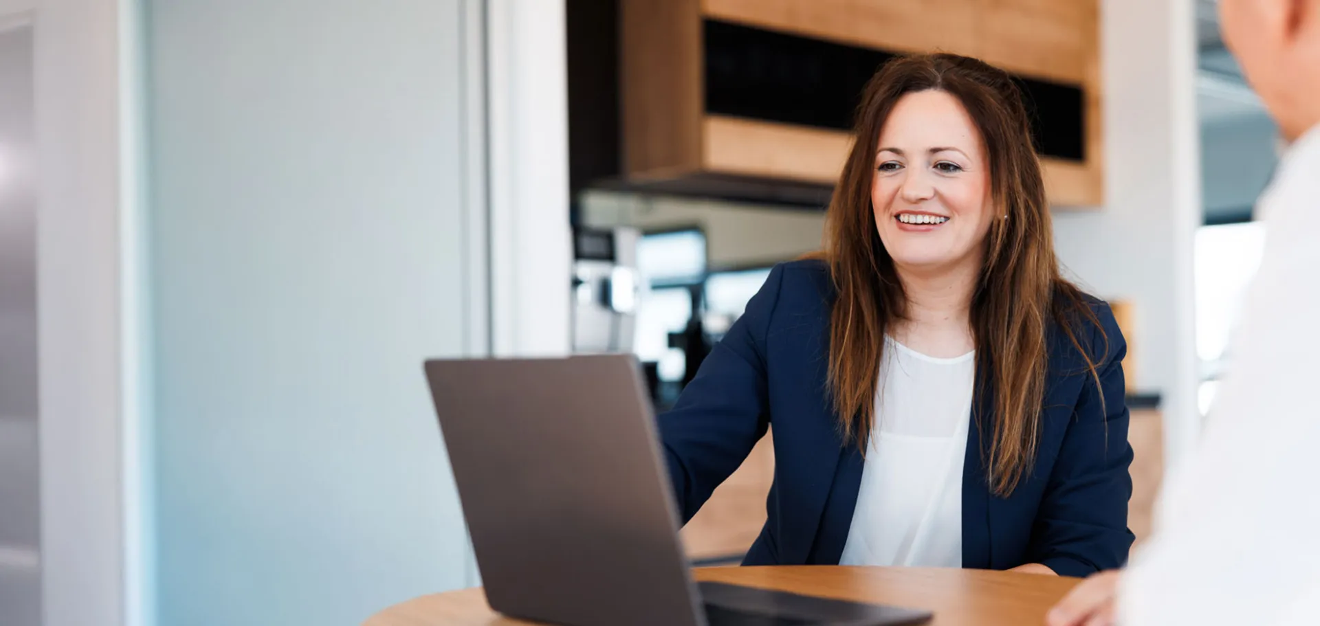 Smiling businesswoman in a blue blazer during a meeting at msg Plaut, discussing innovative digital transformation strategies with a colleague.