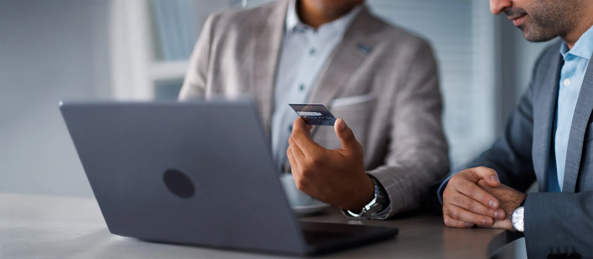 Close-up of two business professionals discussing digital payment and financial data using a laptop, symbolizing finance transformation and analytics in the SAP ecosystem.