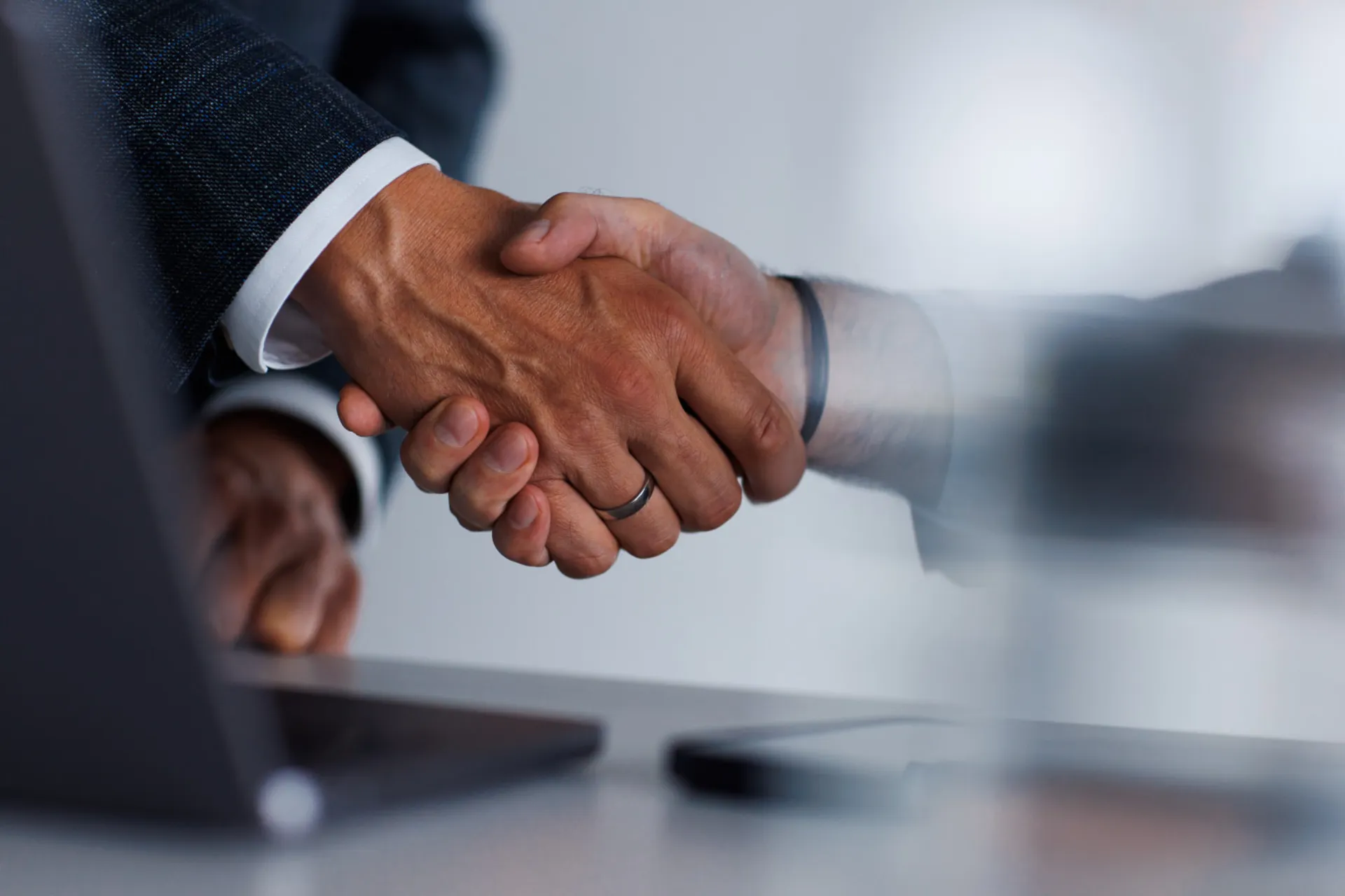 Close-up of two business professionals shaking hands across a table, symbolizing successful partnership or agreement in a corporate setting.